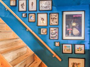 una pared azul con cuadros enmarcados y una escalera en Teal Cottage, en Honiton