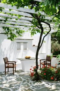 two chairs and a table under a white pergola at Golden Beach Studios & Suites in Tinos Town