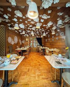 restauracja ze stołami i krzesłami oraz sufitem z chmurami w obiekcie Hotel Giardino Di Pietra w mieście Gramado