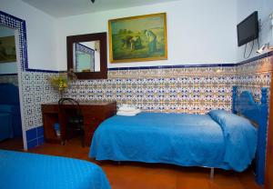 a bedroom with a blue bed and a mirror at Pensión Santa María la Blanca in Seville