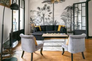 uma sala de estar com um sofá, uma mesa e cadeiras em Résidence Le Paris - Appartements centre ville em Vichy