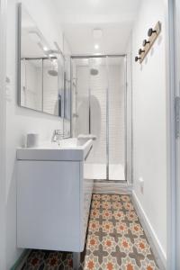uma casa de banho branca com um lavatório e um chuveiro em Résidence Le Paris - Appartements centre ville em Vichy