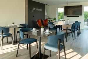 a dining room with tables and blue chairs at Logies Ternier in Nieuwpoort