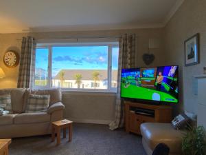 een woonkamer met een flatscreen-tv en een bank bij Osborne Cottage in Southend