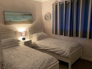 a bedroom with two beds and a clock on the wall at Osborne Cottage in Southend