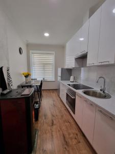 a kitchen with white cabinets and a wooden floor at Cēsu mājas Rīgas ielā in Cēsis