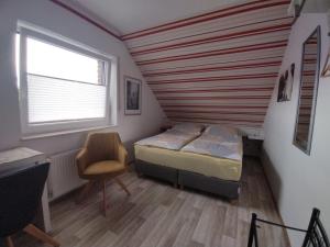 ein Schlafzimmer mit einem Bett, einem Fenster und einem Stuhl in der Unterkunft Gästehaus AM HERMANN in Hörstel
