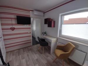 Zimmer mit einem Schreibtisch, 2 Stühlen und einem Fenster in der Unterkunft Gästehaus AM HERMANN in Hörstel