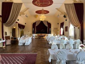 a banquet hall with white tables and chairs and a chandelier at Bahnhofshotel Die Neue Bühne in Bad Saarow