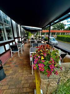 eine Gruppe von Tischen und Stühlen mit Blumen auf einer Terrasse in der Unterkunft Bahnhofshotel Die Neue Bühne in Bad Saarow