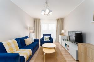 a living room with a blue couch and a tv at Przystań Koło Brzegu in Kołobrzeg