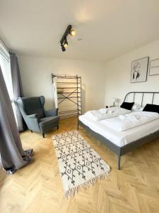 een slaapkamer met een bed, een stoel en een tapijt bij Ginius Homes- Penthouse Düren in Düren - Eifel