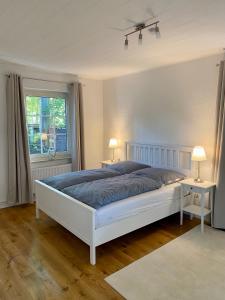 a bedroom with a large white bed with two tables at Ankerplatz in Leer