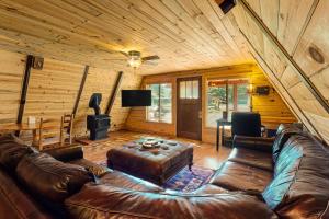 una sala de estar con sofá de cuero en una cabaña de madera en Pinon Pines, en South Fork