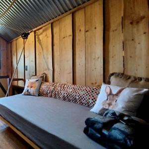 a bed in a room with wooden walls and a couch at La Cabane du Coing in Visé