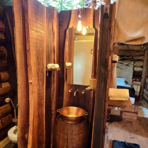 uma casa de banho com um balde de cobre num quarto de madeira em La Cabane du Coing em Visé