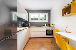 a kitchen with white cabinets and yellow chairs at Maison Giulia ai Giardini in Bologna