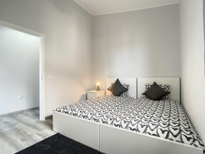een witte slaapkamer met een groot bed met zwarte kussens bij Casa da Avo by Atlantic Holiday in Caniçal