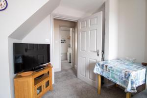 Habitación con TV y puerta con mesa. en Sea La Vie- Cosy, Modern, Harbourside Views, en Brixham