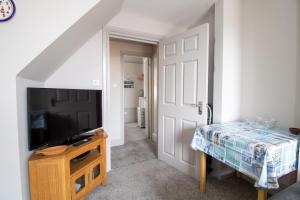 a room with a tv and a door with a table at Sea La Vie- Cosy, Modern, Harbourside Views in Brixham
