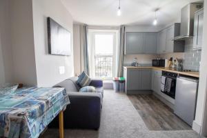 a living room with a couch and a kitchen at Sea La Vie- Cosy, Modern, Harbourside Views in Brixham