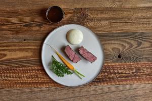 ein Teller mit Fleisch und Gemüse auf einem Holztisch in der Unterkunft EnHotel in Zakopane