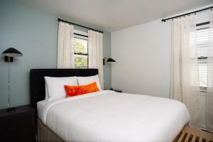 a bedroom with a large white bed with a red pillow at Abode Nashville - Marathon Village Near Downtown in Nashville