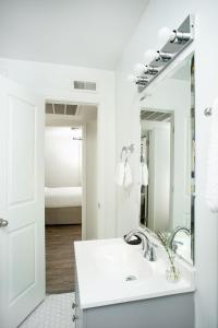 a white bathroom with a sink and a mirror at Abode Nashville - Marathon Village Near Downtown in Nashville