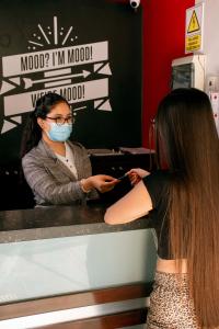 Mood Hotel Lifestyle في تشيكلايو: امرأة ترتدي قناع الوجه تنظر إلى المرآة