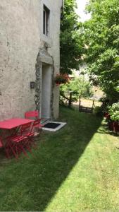 a red table and chairs in the yard of a building at La Suite Lou in Le Noyer