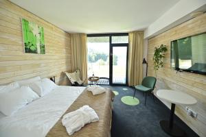 a hotel room with a bed and a table and a tv at Pensiunea Atra Doftana in Teşila
