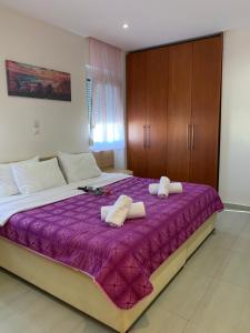 a bedroom with a large bed with purple sheets and wooden cabinets at Cozy Violetas apartment,ideally located. in Ialysos