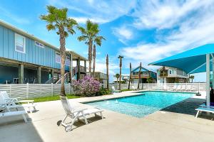 a pool with chairs and palm trees next to a house at Paradise Pointe in Port Aransas