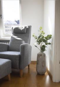 una sala de estar con una silla y un jarrón con una planta en 2ndhomes Stunning Top Floor Residence with Sauna and Balcony, en Helsinki