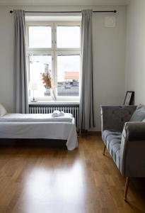 een slaapkamer met een bed, een raam en een bank bij 2ndhomes Stunning Top Floor Residence with Sauna and Balcony in Helsinki
