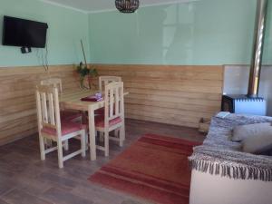 a dining room with a table and chairs and a couch at EL EMBRUJO PATAGON in Coihaique