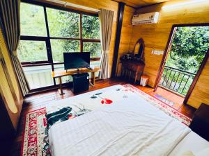 a bedroom with a bed and a desk and windows at BAZAN HOME - Hotel & Bungalow in Pleiku
