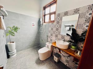 a bathroom with a toilet and a sink and a mirror at BAZAN HOME - Hotel & Bungalow in Pleiku