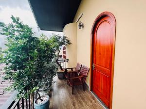 a red door on a balcony with two plants at BAZAN HOME - Hotel & Bungalow in Pleiku