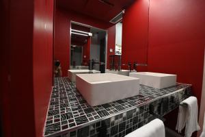 a bathroom with three sinks and a red wall at CHIC HOUSE MATERA - Design e Parking a 200m dai Sassi in Matera +17 photos