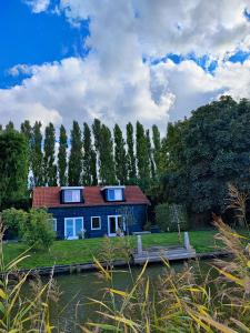 una casa azul a orillas de un río en My Lodge, en Dinteloord