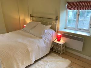 a bedroom with a white bed with two red candles at Beautiful Somerset Cottage with garden views. in Bruton