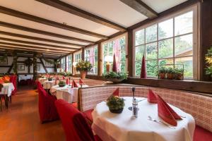a restaurant with tables and red chairs and windows at Thermen Hotel & Restaurant Bad Soden in Bad Soden am Taunus
