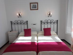 a bedroom with two beds with red and white blankets at Hostal 2 estrellas -Restaurante Las Tres Encinas in Cabeza la Vaca