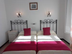 a bedroom with two beds with red and white blankets at Hostal 2 estrellas -Restaurante Las Tres Encinas EN EL CENTRO DEL PUEBLO in Cabeza la Vaca