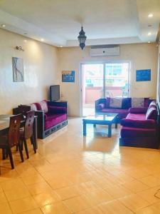 una sala de estar con sofás morados y una mesa. en Appart Majorelle entier au Centre Ville, en Kenitra