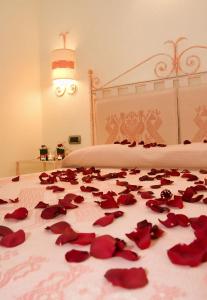 a bed with red rose petals on it at Hotel Soffio di Vento in Arbus
