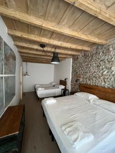 - une chambre avec 2 lits et un mur en pierre dans l'établissement Borgovivo Il tuo Loft in centro città, à Bergame