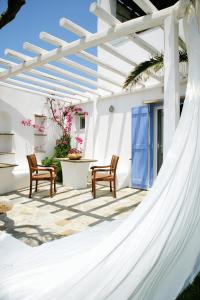 a hammock on a patio with a table and chairs at Golden Beach Studios & Suites in Tinos Town