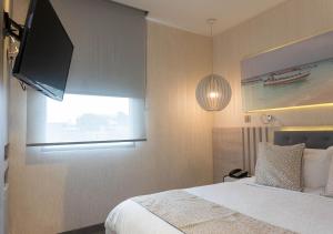 - une chambre avec un lit et une télévision à écran plat dans l'établissement Hotel Perla Suite, à Santa Marta